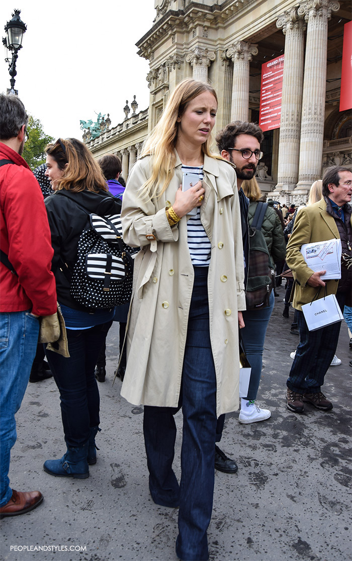 Jennifer Neyt wearing dark color wide leg jeans, stripe sweater, trench coat and mixing it with a lot of golden jewellery, street style look new Instagram